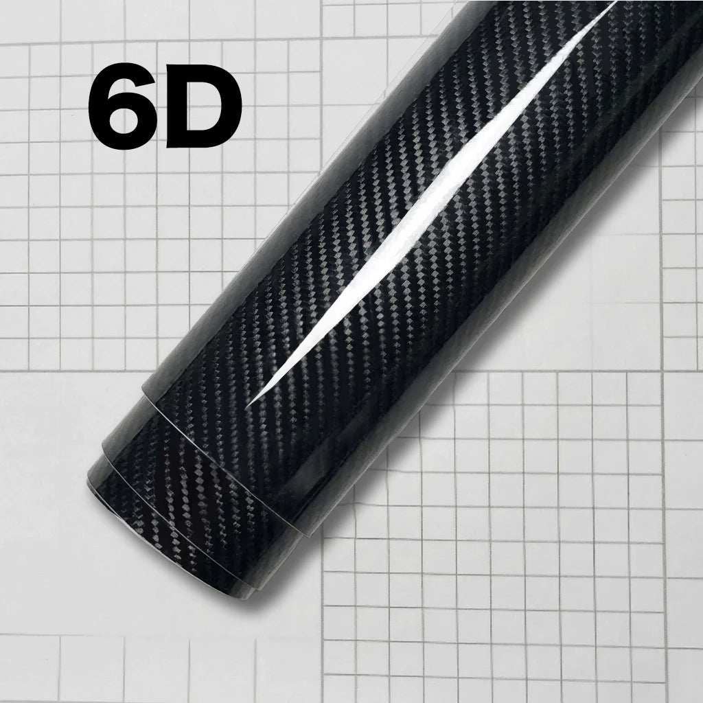 A close-up view of a black carbon fiber vinyl wrap film displaying a glossy finish on a grid background.