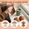 Hands crocheting a brown animal doll with a positive message card next to a cup.