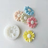 A collection of silicone daisy molds in pastel blue, pink, yellow, and cream colors.