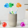 A collection of colorful portable electric toothbrush heads in blue, green, and orange are displayed in a cylindrical case.