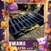 A decorative rug featuring a spider web and ghost design displayed in a frame surrounded by autumn leaves and pumpkins.