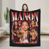 A dark graphic blanket featuring the name MANON and several women in various poses.