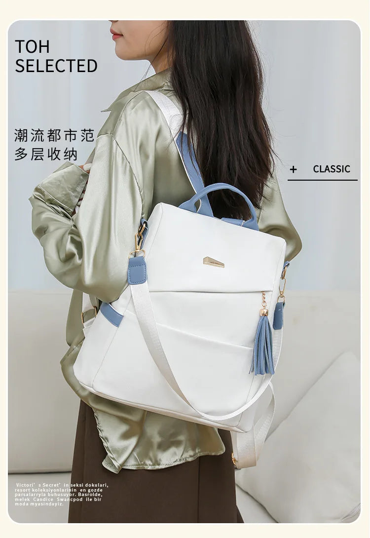 A woman is wearing a white leather backpack with blue accents and a satin green jacket.