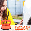 A hand is using an orange car dent puller kit with suction cups to fix a dent on a white car.