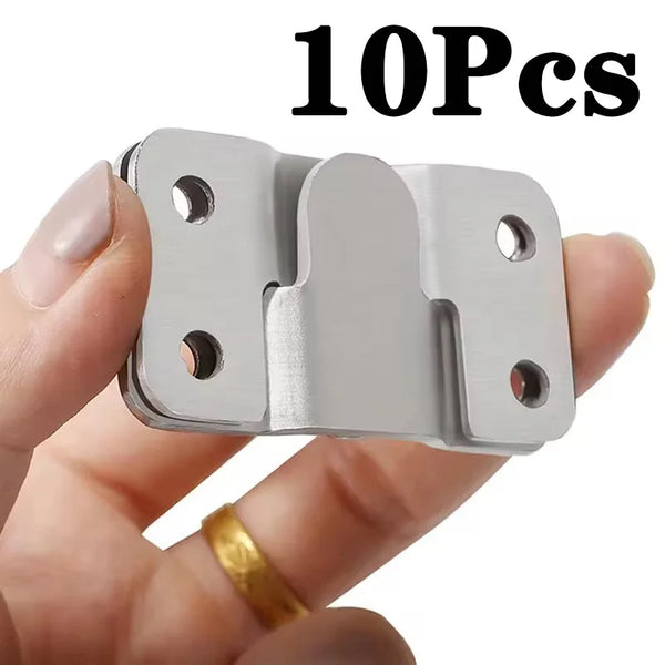 A hand holds a silver stainless steel picture frame hanging buckle set, showing the individual components.