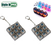 Two silver fidget keychains with a keyboard design and LED lights, shown next to a set of glowing blue and pink LEDs.