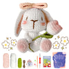A finished white crochet bunny toy with pink accents, surrounded by yarn, tools, and a DIY kit.