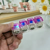 A hand holds several purple LED light-up keyboard keychains or fidget toys.