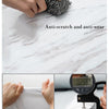 A hand is shown interacting with a textured, anti-scratch and anti-wear product placed on a marble surface.