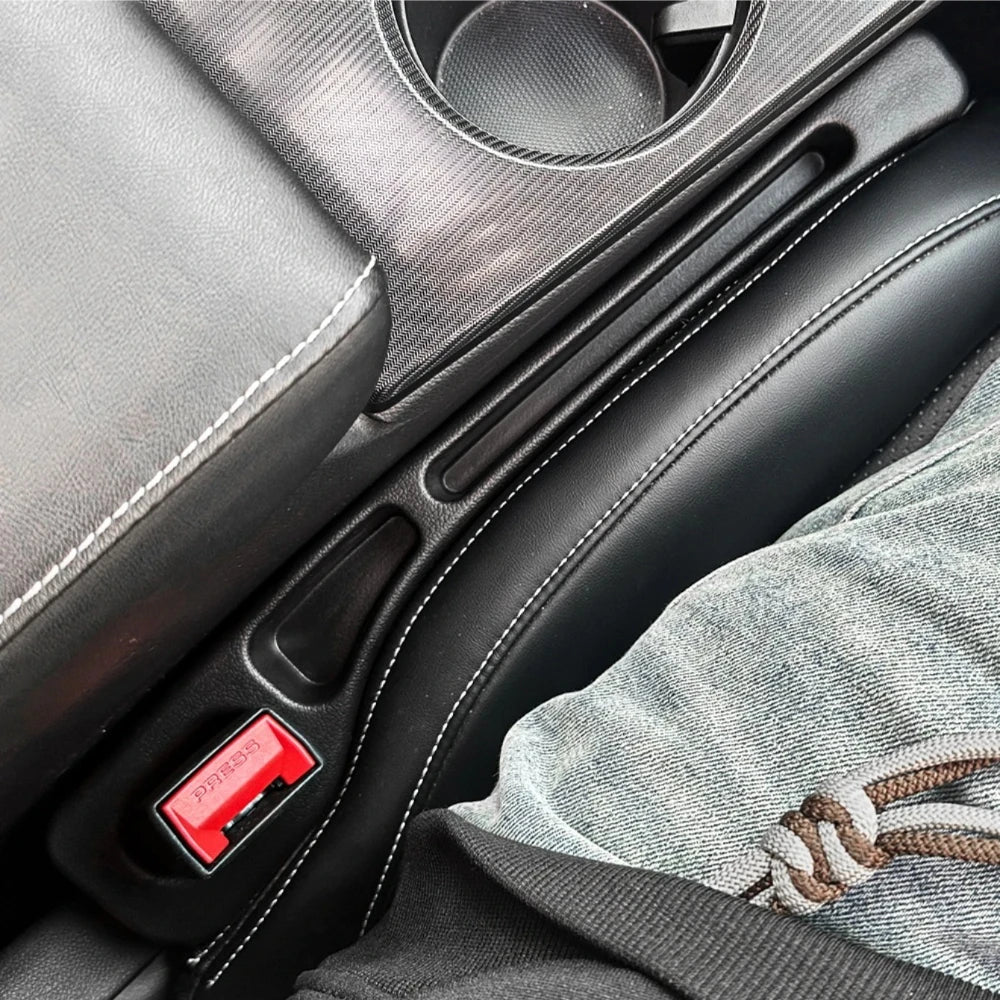 A close-up view of a black car seat gap filler organizer with red accents and stitching, designed for crevice storage.