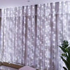 Floor-to-ceiling sheer white curtain illuminated by vertical strings of twinkling fairy lights