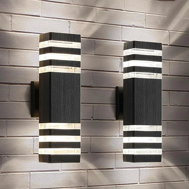 Modern up and down LED wall sconce with black and white striped light panels mounted on a gray brick wall.