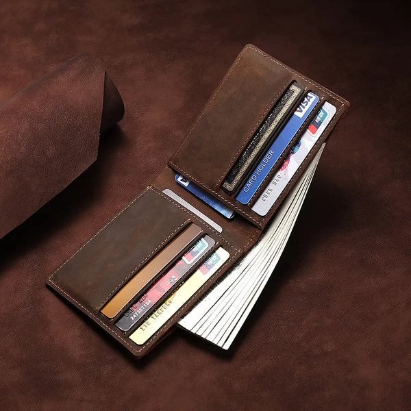 A brown leather bifold wallet holding several cards and a card holder on a dark brown surface.