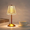 A gold-toned table lamp with a textured glass shade illuminates a white cup on a light surface.
