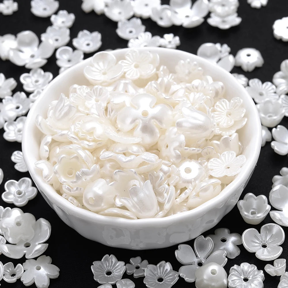 A white bowl filled with acrylic pearl spacer beads scattered on a dark surface.