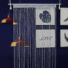 A vertical string curtain made of blue beads hangs, featuring a heart design and the word LOVE.
