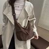 A person wearing a white trench coat is holding a brown leopard print crossbody bag.