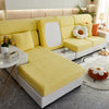 A bright yellow elegant sofa slipcover with white accents and decorative pillows in a modern living room setting.