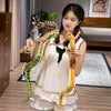 A young woman is holding a lifelike, soft, yellowish-green snake plush toy in her hands.