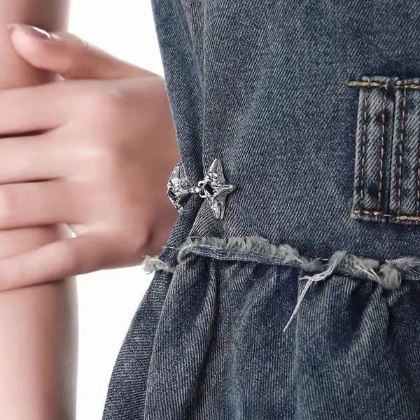Nahaufnahme eines dunkelblauen Denim-Kleidungsstücks mit silbernem vierzackigem Stern-Tailleriemerke an der Seite.