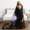 A woman is relaxing on a bed with a black and blue Michael Jackson graphic plush throw blanket draped over her.