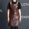 A woman wearing a brown PU leather multi-pocket kitchen apron with leather straps against a dark background.