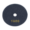 A round, dark gray felt polishing pad with the number 1000 stamped on it.