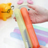 A hand holds two translucent silicone toothbrush cases, one light green and one orange.