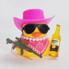 A yellow rubber duck wearing a pink cowboy hat and sunglasses is positioned next to a small firearm.