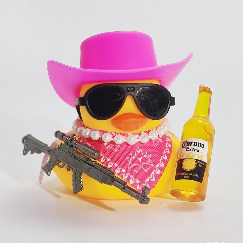 A yellow rubber duck wearing a pink cowboy hat and sunglasses is positioned next to a small firearm.