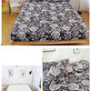 A fitted bed sheet featuring a marbled print with leaves and flowers in black and white on a wooden bed frame.