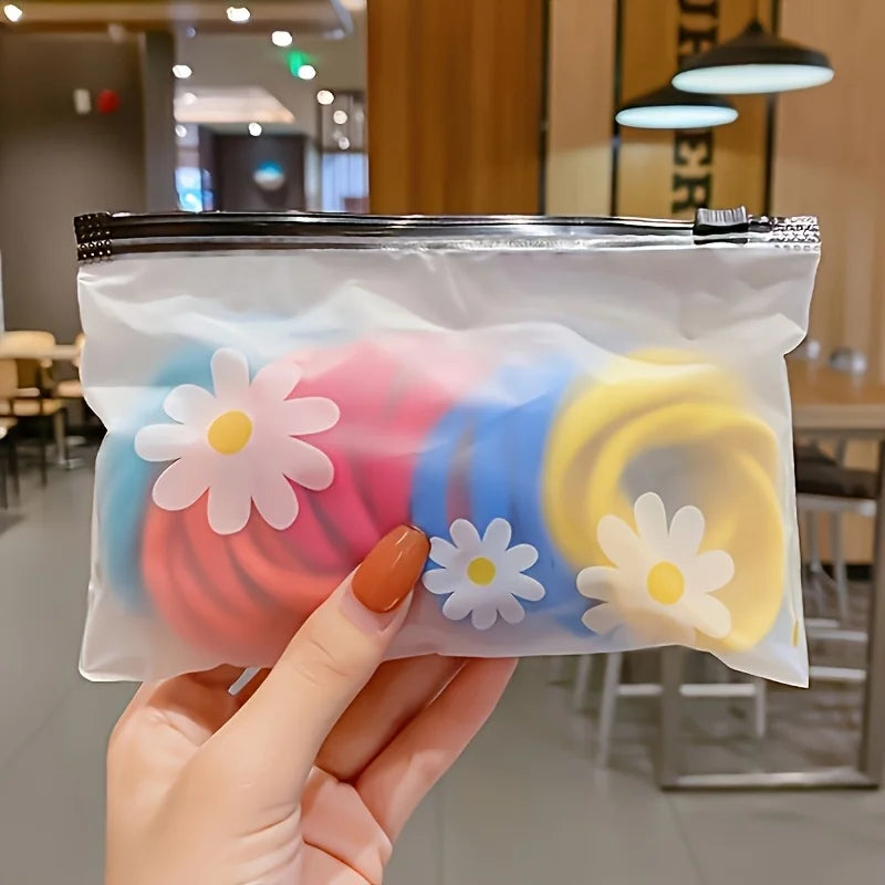 A hand holds a clear plastic zipper bag filled with colorful frosted daisy pattern fabric storage pouches.