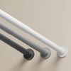 A close-up view of a modern, adjustable stainless steel tension shower curtain rod mounted on a wall.