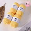 A stack of bright yellow Milk Cotton yarn balls for knitting and crochet, shown next to a dried leaf.