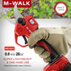 A hand holds a red M-Walk pruning shear tool against a blurred green background.