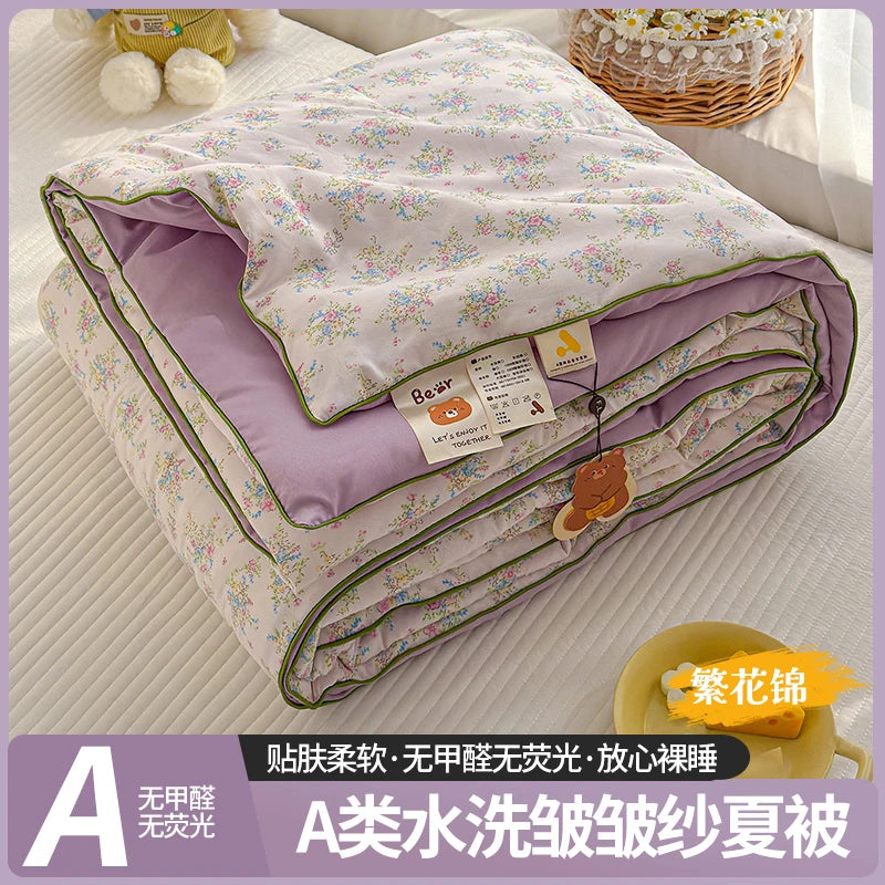 A lightweight summer quilt with a playful cartoon print featuring purple and green trim.