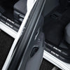 Close-up view of carbon fiber door sill protector stickers installed on a vehicle interior.