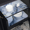 A display of white ceramic plates and candles on a dark marble surface with gold veining.