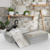 Stacks of marble self-adhesive wall stickers in various shades and patterns displayed against a stone tiled background.