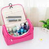 A pink hanging makeup bag is open, showing various cosmetic products inside on a white surface.