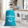 A bright teal drawstring laundry bag resting on a light floor in a kitchen area with laundry appliances visible.