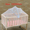 A wooden crib with a sheer mesh mosquito net covering the sides and top for a baby.
