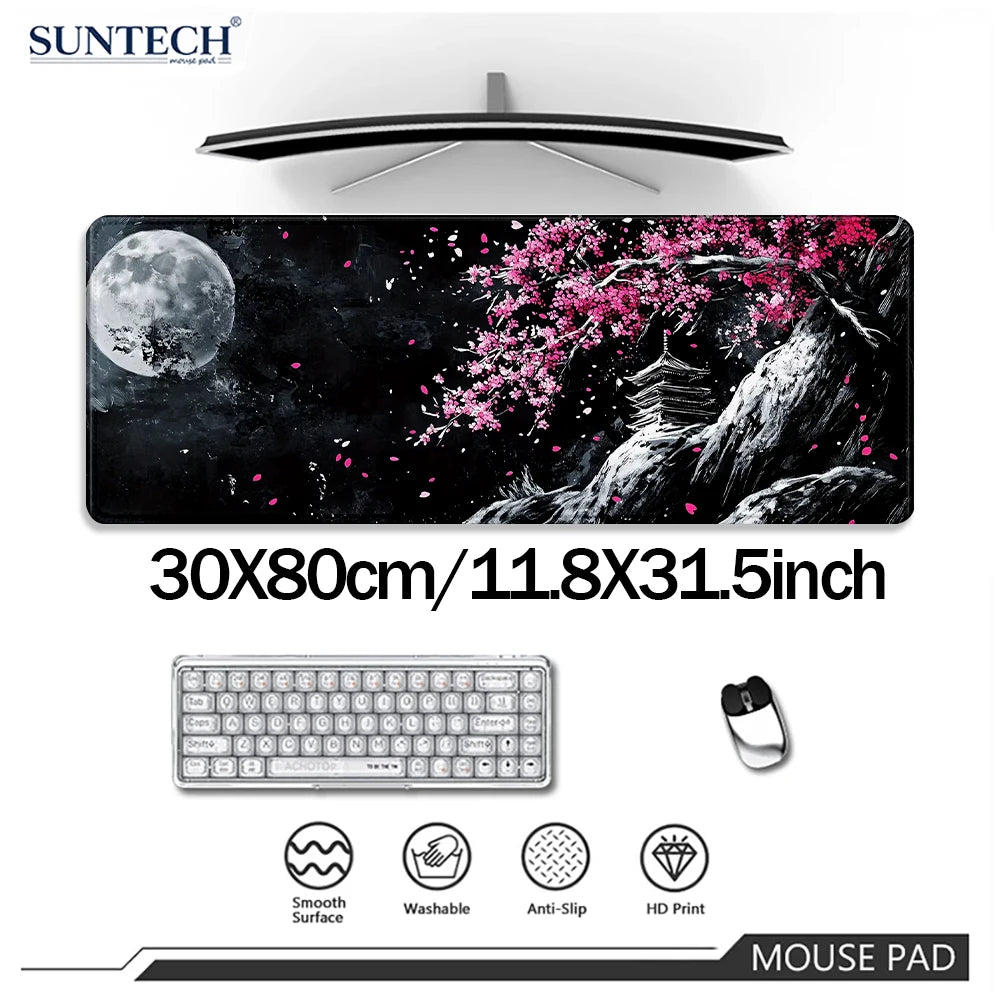 Un tapis de souris noir avec un motif de fleurs de cerisier roses et un ordinateur portable, un clavier et une souris.
