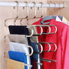 A rack of S-shaped metal hangers holding various colored pants and trousers.
