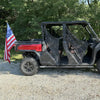 A gray truck with a custom open-air bed and a flag pole holder mounted on the tailgate, parked on gravel.
