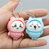 A pair of cute PVC bag pendant dolls, one pink and one light blue, are held in a hand.