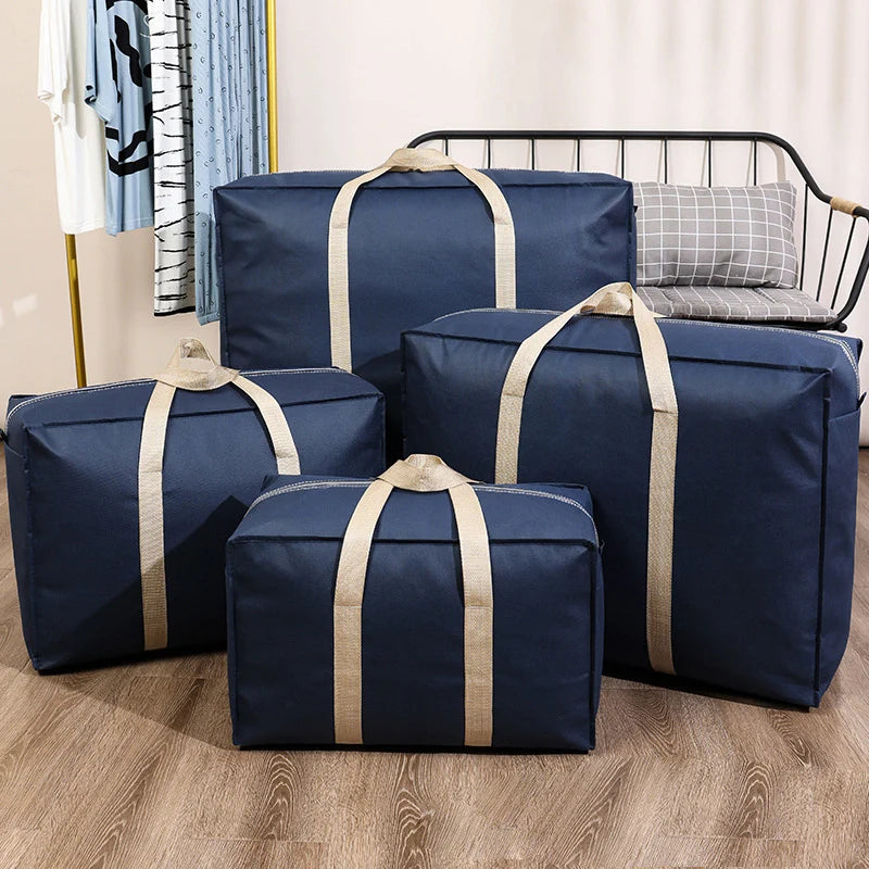 A set of navy blue waterproof moving and storage bags with tan straps are displayed on a wooden floor.