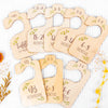 A set of eight wooden baby closet dividers showing size organizers for newborn to 24 months.
