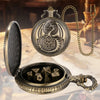 A vintage brass dragon pocket watch dice case with a chain and an open box revealing seven metal polyhedral dice.