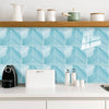 White and blue herringbone marble peel-and-stick wall tiles displayed on a kitchen countertop.
